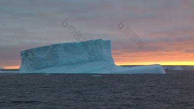 与巨大的冰山在日落时在南极洲冰冷景观